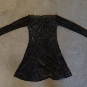 Svart sammetsklänning offshoulder - Supersnygg svart sammetsklänning med offshoulder och långa ärmar. Klänningen har en lätt utsvängd form. 