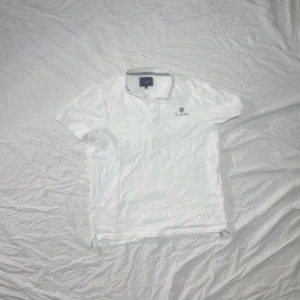 Vit piké t-shirt från Bondelid - Vit piké t-shirt från Bondelid i klassisk stil med krage och knappslå. Liten logga på vänstra bröstet. 