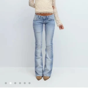 Bootcut ljusblå jeans med broderade fickor - Snygga ljusblå bootcut jeans med låg midja och broderade bakfickor dekorerade med pärlor och mönster. Jeansen har klassisk femficksdesign, dragkedja och knapp framtill. Perfekt för dig som gillar detaljer och en avslappnad stil.