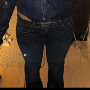 Lucky Brand bootcut jeans mörkblå - Mörkblå bootcut jeans från Lucky Brand med klassiska kontrastsömmar och broderade bakfickor. Lågmidjade och tillverkade i mjukt jeansmaterial med lätt stretch. Perfekta för dig som gillar en tidlös och avslappnad look.