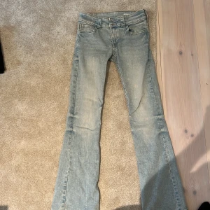Bootcut jeans ljusblå från H&M - Ljusblå bootcut jeans från H&M med låg midja och justerbar midja. Klassisk femficksmodell med snygga detaljer på bakfickan och slitningar för en cool look. Perfekta för dig som gillar en avslappnad och trendig stil.