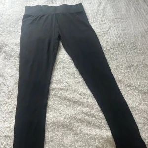 Svarta leggings från Urban Classics - Svarta leggings från Urban Classics med hög midja och bred linning. Tight passform och stretchigt material som sitter skönt. Perfekta till en oversized hoodie eller crop top. Klassisk och enkel design utan detaljer.nya byxor 