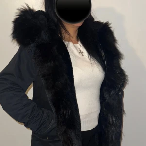 Svart vinterjacka med äkta päls  - Jag säljer min fina svarta vinterjacka som jag inte har användning av längre, den är fodrad med päls inifrån och värmer något extra. Luvan är stor och också helt päls. Det finns en dragkedja och även knappar.