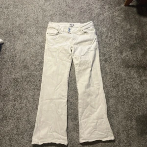 Vita bootcut jeans från  lager157 xl/full - Snygga vita jeans från 157 med bootcut passform och broderad detalj på bakfickan. Jeansen har dubbla knappar framtill och klassiska fickor. Perfekta för dig som vill sticka ut med en fräsch och stilren look.