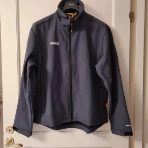 Grå jacka, Herr, DeWalt, storlek L - Vattentålig, andningsbar och garanterad kvalité jacka. Foder är fleece. Jackan har en stor innerficka.