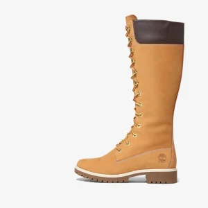Timberland höga snörade boots - Snygga höga boots från Timberland i klassisk beige nubuck med bruna detaljer upptill. Skorna har grov sula, rund tå och snörning hela vägen upp för en cool look. Perfekta för höst och vinter när du vill ha både stil och funktion.