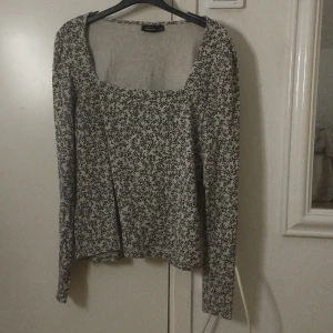 Blommig långärmad blus från KappAhl - Säljer en vit blus med svart blommigt mönster från KappAhl i storlek M. Blusen har lång ärm, fyrkantig ringning och är i mjukt bomullsmaterial. Perfekt för dig som gillar romantiska och stilrena vibes. Fräsch och enkel att matcha med jeans eller kjol.