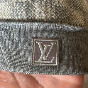 Grå  mössa från Louis Vuitton - LV mössa i nästan helt ny skick. Den har används ett fåtal gånger och är äkta. Säljs på grund av att den inte används längre. Den är ÄKTA. Kan kollas igenom innan man köper. Perfekt till vintern. Priset kan diskuteras. 