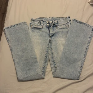 Ljusblå bootcut jeans med låg/middel midja - Snygga ljusblå jeans med bootcut och låg midja. Jeansen är i storlek 164 men passar mig perfekt och har har oftast S/XS. Jeansen har två knappar i midjan, breda hällor och klassisk femficksdesign. Materialet är denim och passformen är normal med lätt utsvängda ben. Perfekta för en avslappnad och trendig look.