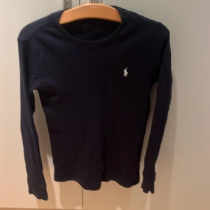 Mörkblå långärmad tröja Polo Ralph Lauren - Snygg mörkblå långärmad sweatshirt från Polo Ralph Lauren med klassisk broderad logga på bröstet. Tröjan är ribbad och har en rund hals. Perfekt för dig som gillar stilrena och tidlösa plagg med premiumkänsla. Storlek S som egentligen passar ungefär XS(runt 160-170). Hör av er vid funderingar och priset kan gå ner vid snabb affär