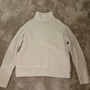 Vit polotröja från Gina Tricot XS - Säljer en vit polotröja från Gina Tricot i storlek XS. Tröjan har ribbad polokrage, ribbade muddar och nederkant samt långärmad design. Perfekt för dig som gillar en clean och enkel look med lite extra mysfaktor.