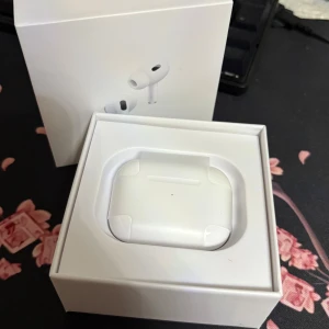 AirPods Pro 2 - Apple AirPods Pro 2 i nyskick, komplett med originalförpackning, extra öronkuddar och laddkabel. Aktiv brusreducering, trådlös laddning och MagSafe-stöd. Inga synliga repor eller slitage – ser oanvända ut. Perfekt för musik, samtal och träning.