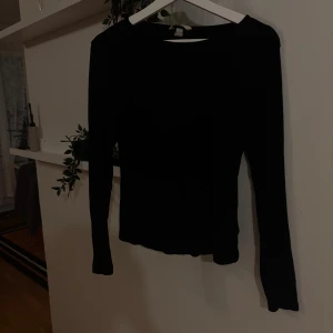 Svart ribbad långärmad tröja H&M - En svart, ribbad långärmad tröja från H&M i storlek M. Tröjan har en slim passform och är tillverkad i mjukt, stretchigt material som sitter snyggt på kroppen. Perfekt basplagg med enkel rund halsringning och stilren look.