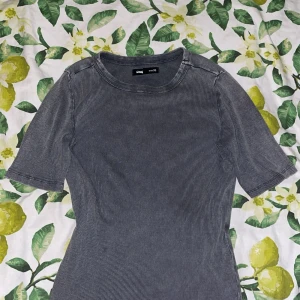 Grå ribbad topp från Sinsay XS - Säljer en grå ribbad topp från Sinsay i storlek XS. Toppen har korta ärmar, rund halsringning och ett diskret randigt mönster. Materialet är mjukt och stretchigt, perfekt för en chill och stilren look.