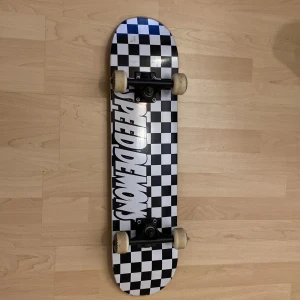 Speed Demons Skateboard - Speed Demons skateboard med klassiskt svartvitt rutmönster. Utrustad med 52mm hjul och ABEC 7 kullager. Brädan och hjulen är i gott skick med endast mindre slitage på grip tape och kanter. Perfekt för både nybörjare och erfarna åkare.