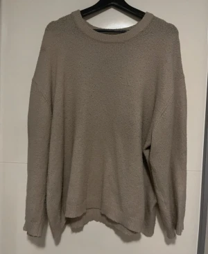 Beige stickad tröja från 157 - Mysig beige stickad tröja från 157 i storlek L. Tröjan har en rund halsringning och långa ärmar med ribbade muddar. Perfekt för lager-på-lager och chill dagar. Enkel och stilren design som passar till jeans eller mjukis.