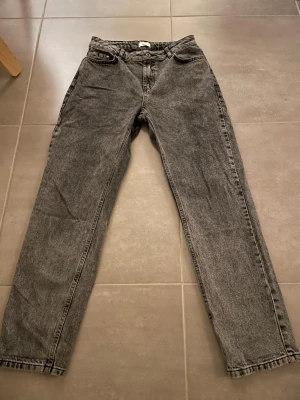 Grå straight jeans från grunt - Snygga grå jeans från grunt med klassisk femficksdesign och rak passform. Jeansen har en tvättad look och svarta detaljer på bakfickan. Perfekt för dig som gillar en avslappnad stil med vintagekänsla.