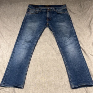 Blå jeans från Nudie Jeans Co W30 L32 - Säljer ett par klassiska blå jeans från Nudie Jeans. Modellen har raka ben, fem fickor och coola detaljer på bakfickorna. Perfekta för dig som är grish men ändå vill sticka ut lite. Priset kan diskuteras.