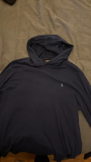 Mörkblå hoodie från Polo Ralph Lauren - Snygg mörkblå hoodie från Polo Ralph Lauren i mjuk bomull. Klassisk design med huva och diskret logobrodyr på bröstet. Perfekt för dig som gillar stilrena och bekväma plagg. Passar dig som vill ha en enkel men ikonisk look.skriv vid frågor.pris kan diskuteras.