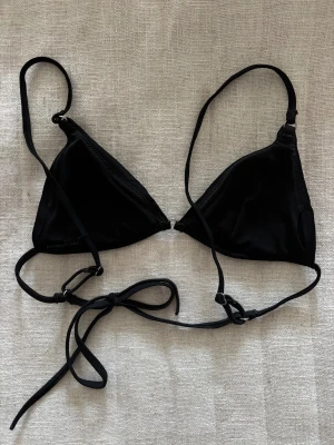 Svart trekantsbikini med knytband - Mycket bra skick! Svart trekantsbikini med tunna axelband och knyt i ryggen, vadderade.