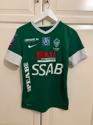 Grön IK Brage matchtröja Nike - Säljer en grön IK Brage fotbollströja från Nike med vita detaljer och tryck. Tröjan har korta ärmar, klubbmärke på bröstet, flera sponsorer och stor siffra 9 på ryggen. Materialet är lätt och andas, perfekt för träning eller match.