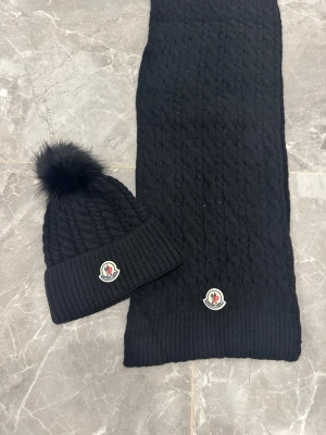 Moncler beanie+ scarf set - 🎨 Färg: Svart 📏 Storlek: One size ♻️ Skick: Mycket fint skick 🧵 Material: Kabelstickad ull/ullmix med 📦 Skickas samma dag vid köp