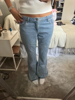 Ljusblå bootcut jeans från H&M  - Säljer ett par ljusblå jeans från H&M Divided i storlek 38. Modellen är bootcut och har en låg midja med snygga sömdetaljer längs benen. 