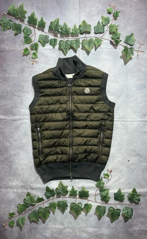 Moncler Maglia Cardigan i Grå och Beige Storlek S [ÄKTA] - 🎨 Färg: Grå och Beige 📏 Storlek: S ♻️ Skick: 8/10 – lättare bruksspår men inga större defekter 🧵 Material: Mjuk sweatshirt-tyg framtill och i kroppen, med nylonärmar och huva  ✨ Detaljer:         •        Hybridmodell med mjukt tyg och lätt, vindresistent nylon         •        Avtagbar eller fast huva (huvan är nylon)         •        Dragkedja fram         •        Två framfickor med knappdetalj         •        Moncler-patch på vänster ärm         •        Ribbstickad nederkant och muddar