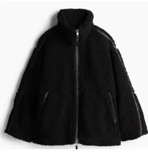 Svart teddyjacka med dragkedja h&m - Svart teddyjacka från h&m med hög krage och hel dragkedja framtill. Jackan har två sidofickor och en loose passform.