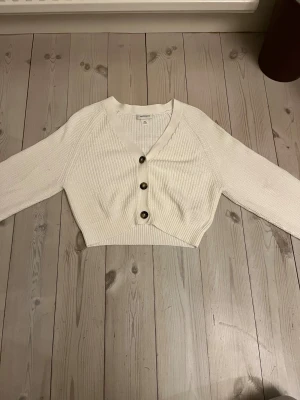 Vit kofta från Monki💞💞💞 - Säljer en vit croppad kofta från Monki i storlek XXS. Koftan är stickad och har v-ringning!! Trender väldigt mycket just nu och går inte att få tag i just denna längre🥰🥰