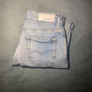 Replay ljusblå jeans, waist 26/30 - Säljer ett par ljusblå Replay jeans i modellen Anbass. Jeansen har klassisk femficksdesign, diskreta slitningar och är tillverkade i ekologisk bomull. Passformen är slim och benen är raka med snygg tvättad look.