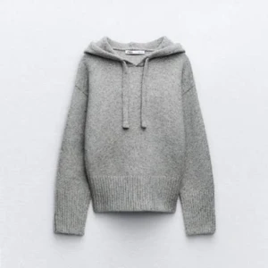 Grå stickad hoodie med snörning - Mysig grå stickad hoodie från Zara med huva och snörning. Tröjan har ribbade muddar och midja, samt lång ärm. Perfekt för kyliga dagar och enkel att styla med jeans eller leggings.