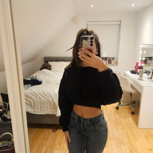 Svart croppad sweatshirt - Säljer en svart croppad sweatshirt med lång ärm och loose passform. Tröjan har en enkel design utan tryck eller detaljer och är perfekt att matcha med jeans eller kjol. Mjuk och skön, passar dig som gillar en avslappnad stil.