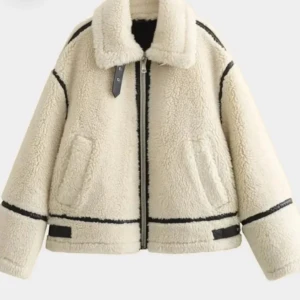 Beige teddyjacka med svarta detaljer - Säljer en beige teddyjacka med svarta kontrastdetaljer och dragkedja framtill. Jackan har stor krage, två fickor och en loose passform som ger en chill vibe. Perfekt för kalla dagar när du vill vara både varm och snygg.