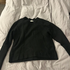 Svart stickad tröja från H&M - Svart stickad tröja från H&M i storlek XS. Tröjan har rund halsringning och långa ärmar med ribbade muddar. Enkel och stilren design som funkar till många olika looks. Perfekt för dig som gillar basic och svart.