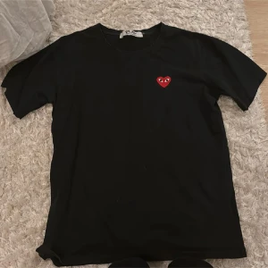 Comme des Garçons play - Svart t-shirt från Comme des Garçons Play med klassisk rund hals och korta ärmar. På bröstet sitter det ikoniska röda hjärtat med ögon, broderat. T-shirten är gjord i mjuk bomull och har en clean, normal passform. Fint skick, pris kan diskuteras.