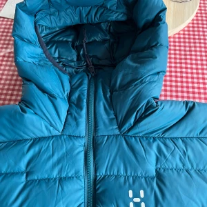 Blå dunjacka Haglöfs W ROC Flash - Säljer en blå dunjacka från Haglöfs, modell W ROC Flash Down Hood. Jackan har huva med snörning, dragkedja framtill och quiltad design. Perfekt för kalla dagar och har Pertex-material för extra hållbarhet. Snygg logga på bröstet och stilren look. Helt ny oanvänd med etikett med kvitto. Nypris 2999kr. Vid snabb affär är priset förhandlingsbart. Passa på!!!! Large men passar Medium också.
