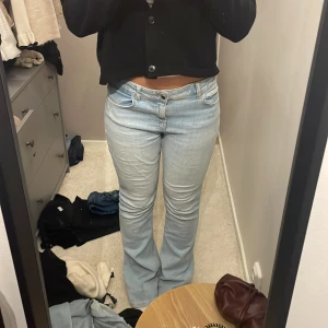 Ljusblå bootcut jeans - Säljer ett par ljusblå jeans med bootcut-modell och klassisk femficksdesign. Jeansen har låg midja och är tillverkade i mjukt denimtyg med lätt tvättad look. Perfekta för dig som gillar en retroinspirerad stil med utsvängda ben.