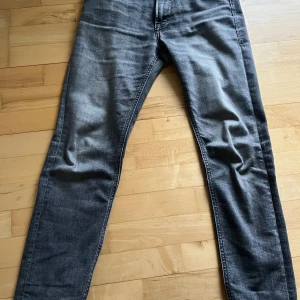 Grå jeans Jack & Jones Regular Clark - Snygga grå jeans från Jack & Jones i modellen Regular Clark. Klassisk femficksdesign med raka ben och normal passform. Jeansen är tillverkade i mjukt denimtyg och har en diskret tvättad look som ger en cool vibe. W29 L32