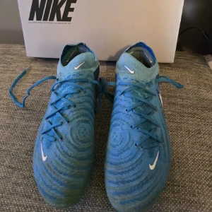 Blå Nike fotbollsskor med snörning - Snygga blå Nike-skor som ger bra touch och passform. Lätta, bekväma och perfekta för både träning och match. Använda men fortfarande i bra skick.  Köpta: 3249 kr.                                  Pris: 1500 kr Kan hämtas eller skickas! 