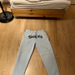 Ljusblå Hoodrich mjukisbyxor med snörning - Snygga ljusblåa mjukisbyxor från Hoodrich med stor svartvit logga framtill. Byxorna har elastisk midja med snörning och raka ben. Perfekta för chill eller streetwear och tillverkade i mjukt bomullsmaterial.