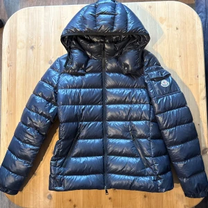 Moncler Bady Jacket - Moncler Bady jacket, selling this iconic moncler Bady jacket, classic and nice jacket for women. Size 4 which corresponds to a Large, can send a picture of the person if desired, no signs of wear, this is 100% clean, completely nice and pretty. Bought at Høyer in Oslo (Norway), tightening both at the waist and at the hood, the hood is also removable. New price is 17,650kr so here you have the opportunity to make a bargain. The jacket is navy / Dark blue. 700++ sales references so here your safe