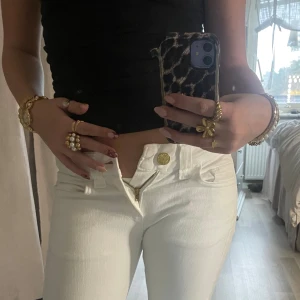 Vita Crocker Cobra zip jeans - Säljer ett par vita lågmidjade jeans från Crocker, modell Cobra Zip. De har raka ben, låg midja och snygga dragkedjor på bakfickorna med gulddetaljer. Det står att storleken är w26, jag har vanligtvis w25/w26 och dessa går ej att stänga. 🙌🏼Alltså väldigt små i storlek 💗