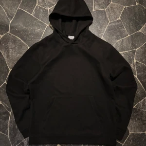 Svart Suede Ciszere Hoodie - En klassisk svart hoodie med stor huva och magficka. Tröjan har en enkel och clean design utan tryck eller mönster, perfekt för en chill och avslappnad stil. Storlek S. Säljs för den inte används längre