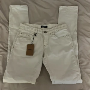 Vita jeansbyxor  - Snygga vita jeansbyxor med raka ben. Köpta på Sellpy men aldrig använt då de var för småa. Perfekta för en clean och fräsch look. Har små fläckar på nedre delen av baksida ben. (Syns knappt)