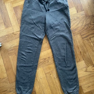 Grå mjukisbyxor från H&M Divided S - Mörkgrå mjukisbyxor från H&M Divided i storlek S. Byxorna har resår och snörning i midjan, samt muddar vid bensluten. Tillverkade i mjukt bomullsmaterial som är perfekt för chill dagar. Klassisk basic-stil med normal passform.