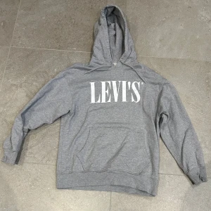 Grå hoodie från Levi's med tryck - Grå hoodie från Levi's i storlek S med stort vitt logotryck på bröstet. Sparsamt använd, väldigt bra skick.