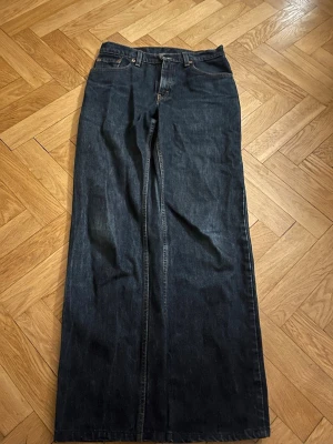  Levi's jeans loose fit - Säljer ett par mörkblå jeans från Levi's med loose passform och hög midja. Klassisk femficksmodell i kraftigt denimtyg. Perfekta för dig som gillar en tidlös och avslappnad stil. 