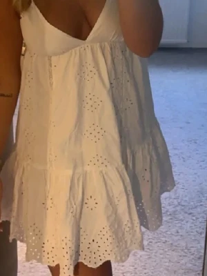 Vit somrig klänning från Zara- broderade detaljer🤍🎀 - Supersöt vit kortklänning med broderade hål och volangkant. Klänningen är ärmlös med v-ringad hals och har en luftig passform, perfekt för varma dagar. Tillverkad i bomull för en skön och lätt känsla. Från Zara i storlek M men passar även S, går att justera i ryggen🤍🎀