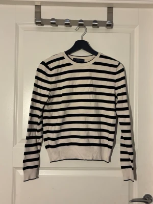 Randig tröja från Zara - Snygg långärmad tröja från Zara med klassiska svarta och vita horisontella ränder. Tröjan har rund halsringning och ribbade muddar vid ärmslut och nederkant. Perfekt för en stilren och enkel look.